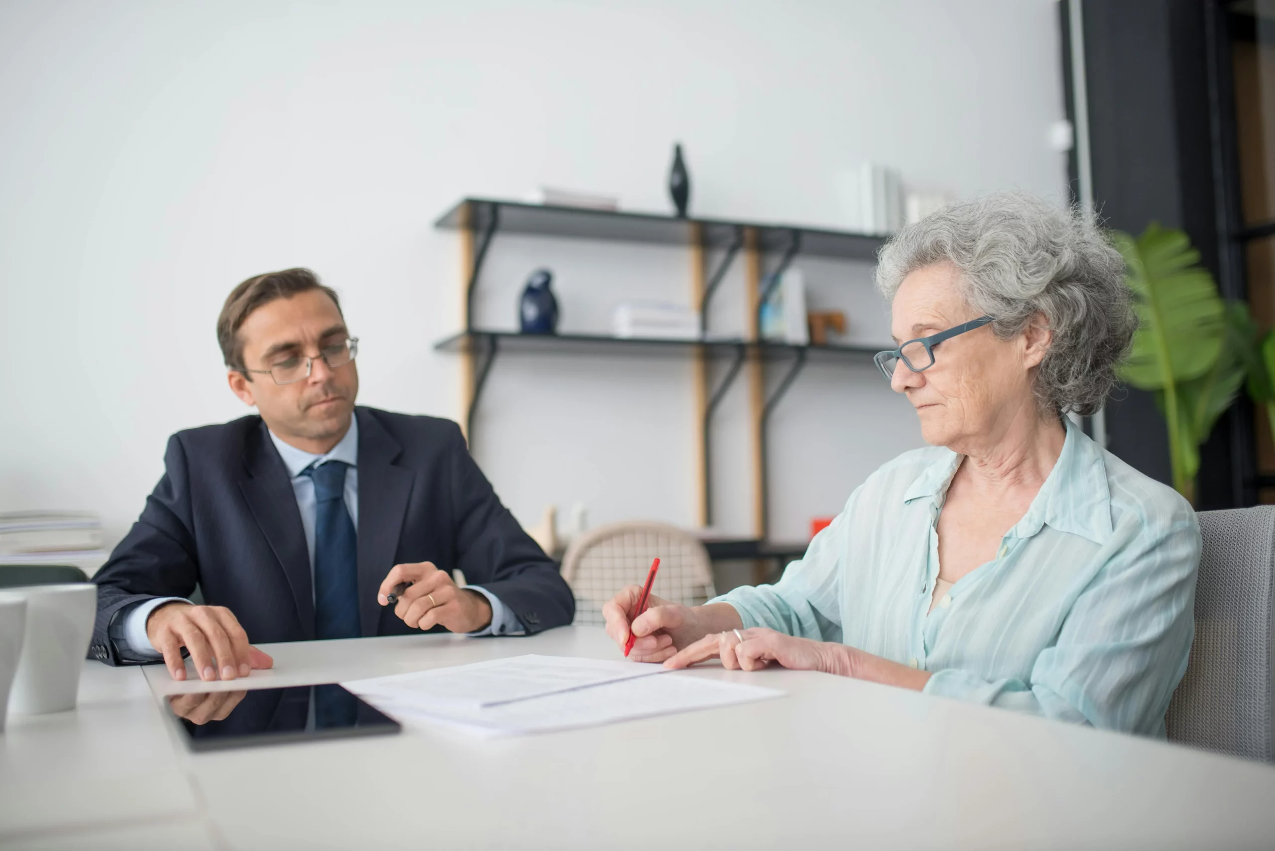 Signature de contrats et formulaires administratifs lors d'un rendez-vous.